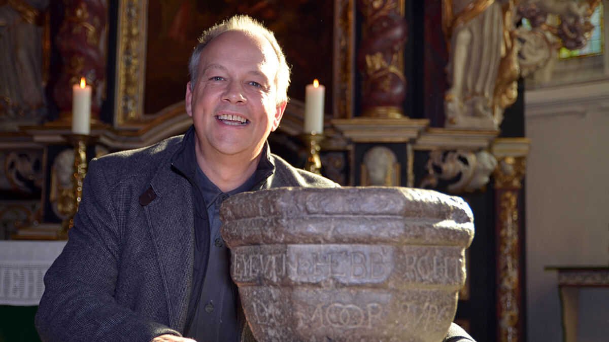 Stolz präsentiert Pastor Torsten Krause das 500 Jahre alte Weihwasserbecken