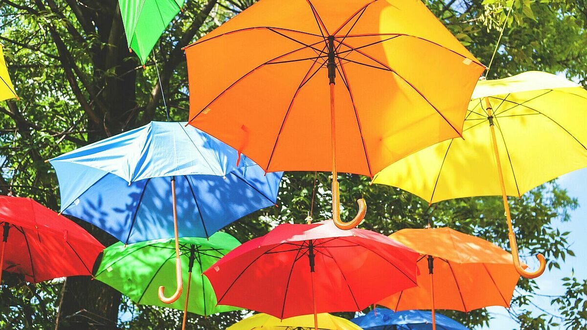Bunte Regenschirme hängen als Deko in der Luft