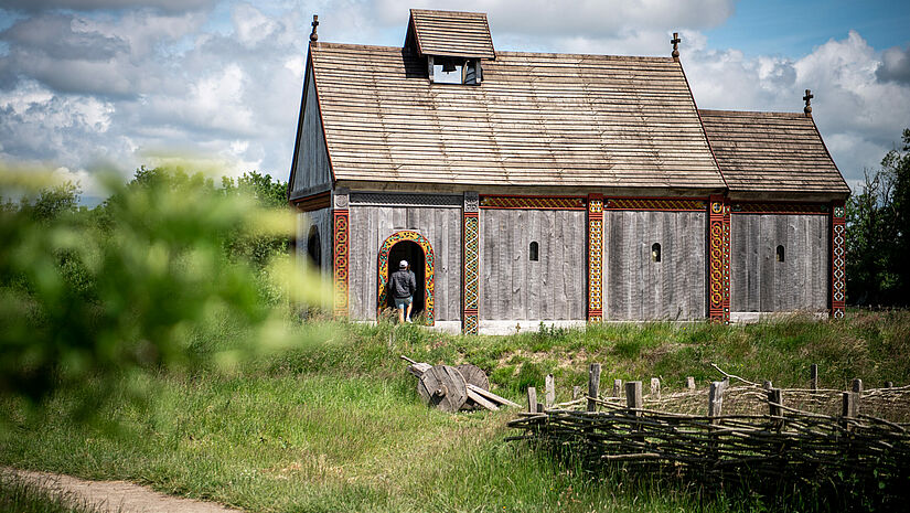Eine kleine Kirche mit Holzwänden und ohne Turm, an den tragenden, vertikalen Ecken verziert mit verschlungenen Wikingerornamenten