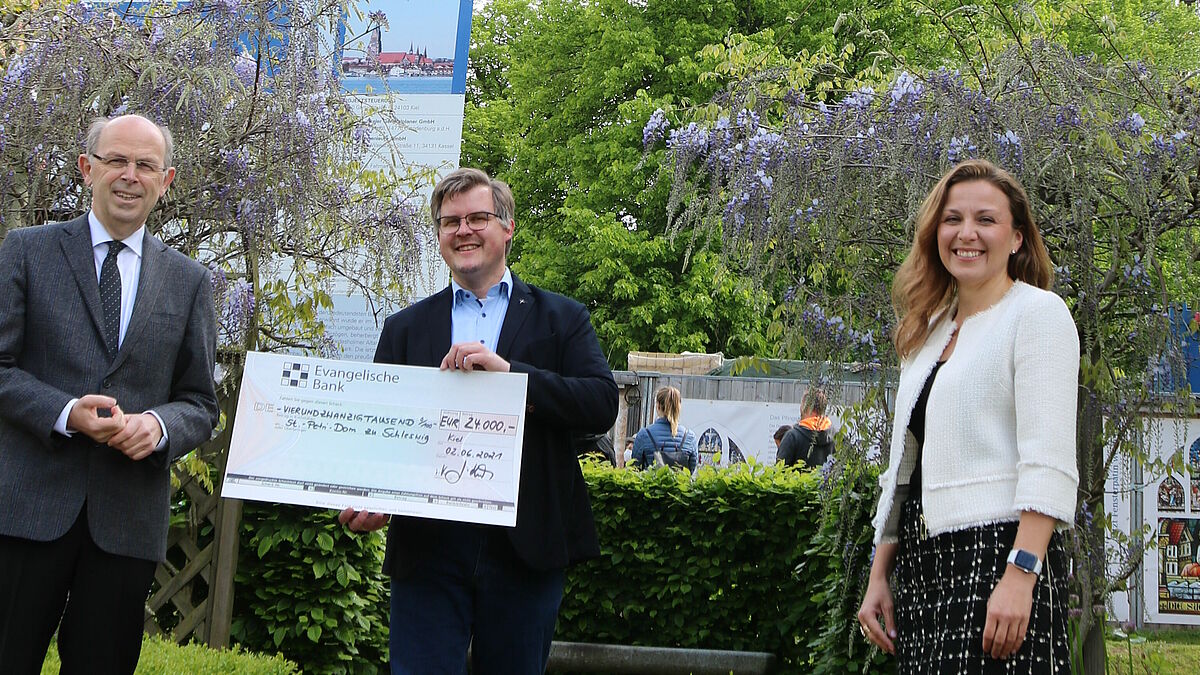 Vertriebsdirektorin Janett Köcher, Evanglische Bank, überreicht bei einem Besuch in Schleswig einen Scheck für die Restaurierung des Tauffensters im Schleswiger Dom. 