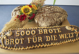 Aktion "5.000 Brote - Konfis backen Brot für die Welt".  Die Zahl 5.000 spielt auf die biblische Geschichte der Speisung der 5.000 durch Jesus an. 