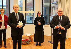 Nebeneinander mit Abstand stehen die Landeskirchliche Beauftragte Claudia Bruweleit, Bischof Gothart Magaard, Schwester Maria Magdalena und Landtagspräsident Klaus Schlie. Sie halten Sterne aus Holz mit der Aufschrift Hoffnungsleuchten in den Händen.