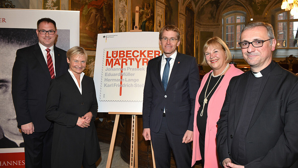 Bei der Vorstellung der neuen Sonderbriefmarke „Lübecker Märtyrer“ im Audienzsaal des Rathauses: Lübecks Bürgermeister Jan Lindenau (v. l.), Bischöfin Kirsten Fehrs, Daniel Günther, Ministerpräsident in Schleswig-Holstein, Bettina Hagedorn (SPD), Parlamentarische Staatssekretärin im Bundesfinanzministerium, und Erzbischof Dr. Stefan Heße.