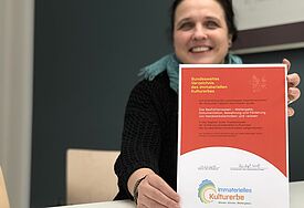 Im Vordergrund die Urkunde, die wird gehalten von Frau Kreuzer, die leicht unscharf im Hintergurnd lächelt
