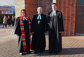 Pastorin Julia Ahmed, Bischof Gothart Magaard und Pastor Hans Hillmann vor der Marienkirche in Bad Segeberg