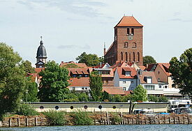 Blick auf die St. Georgenkirche vom Wasser der Müritz. Im Hintergrund ist der Kirchturm der St. Marienkirche zu sehen. 