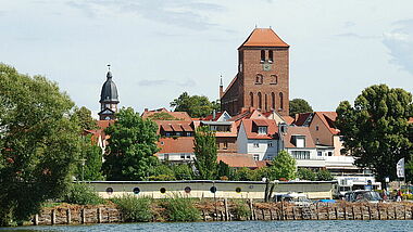 Blick auf die St. Georgenkirche vom Wasser der Müritz. Im Hintergrund ist der Kirchturm der St. Marienkirche zu sehen. 