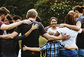 Eine Gruppe von Menschen draußen bilden einen Kreis, halten einander fest