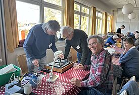 Drei Männer reparieren einen Plattenspieler