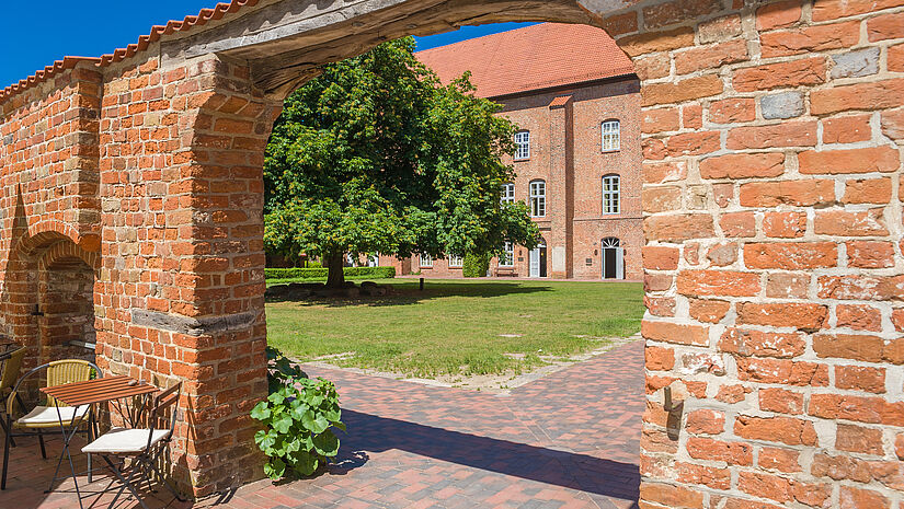 Durch einen Torbogen aus gemauerten roten Ziegelsteingen geht man in den Innenhof des Klosters in Cismar.