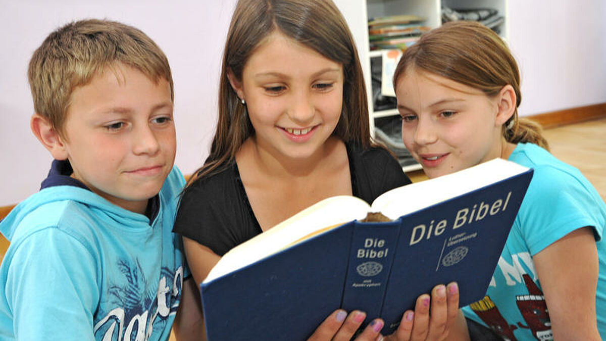 Schüler einer dritten Klasse der Evangelischen Waldschule Eichelkamp in Wolfsburg (Niedersachsen) schauen am 2.7.2012 gemeinsam in die Bibel.