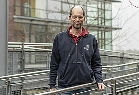 Pastor Matthias Ristau steht in einer blauen Jacke mit Logo der Seemanssmission vor einem Gebäude.