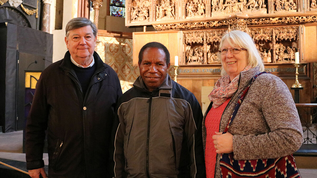 Frauke und Johannes Pfeifer zeigen Bischof Jack Urame (Mitte) die Sehenswürdigkeiten in Schleswig - hier den Brüggemann-Altar im St.-Petri-Dom.