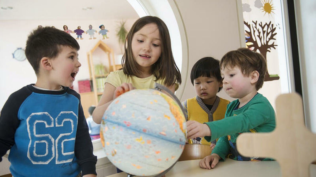 Flüchtlingskinder studieren eine Weltkugel in einem evangelischen Kindergarten (Symbolbild)