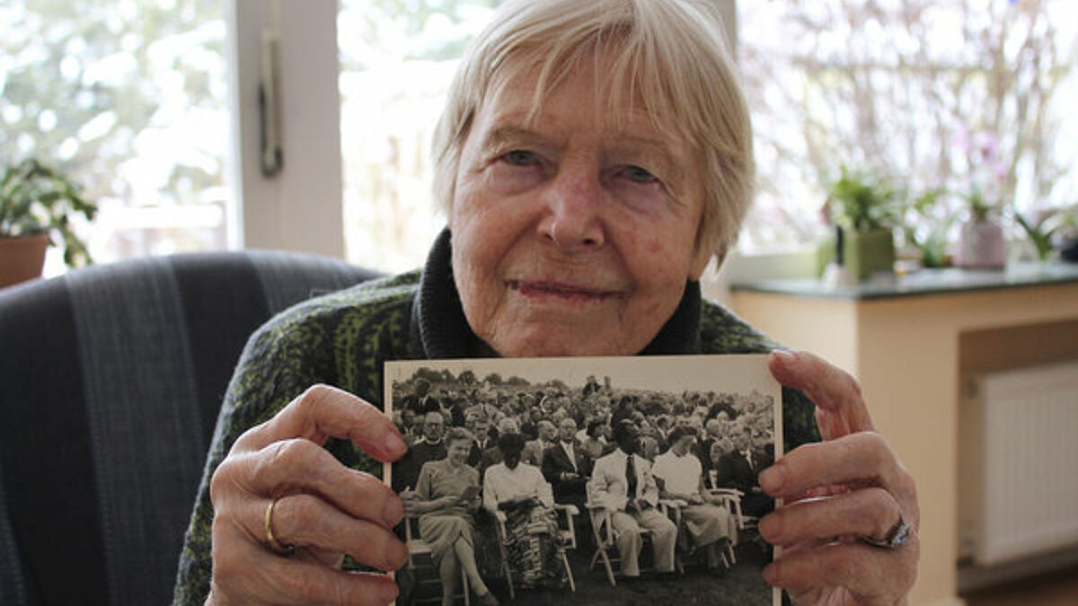 Donate Linck mit einem Foto vom Kirchentag 1953 in den Händen, bei dem sie als 25-jährige Studentin (links im Foto) für einen afrikanischen Minister ins Englische dolmetschte. 