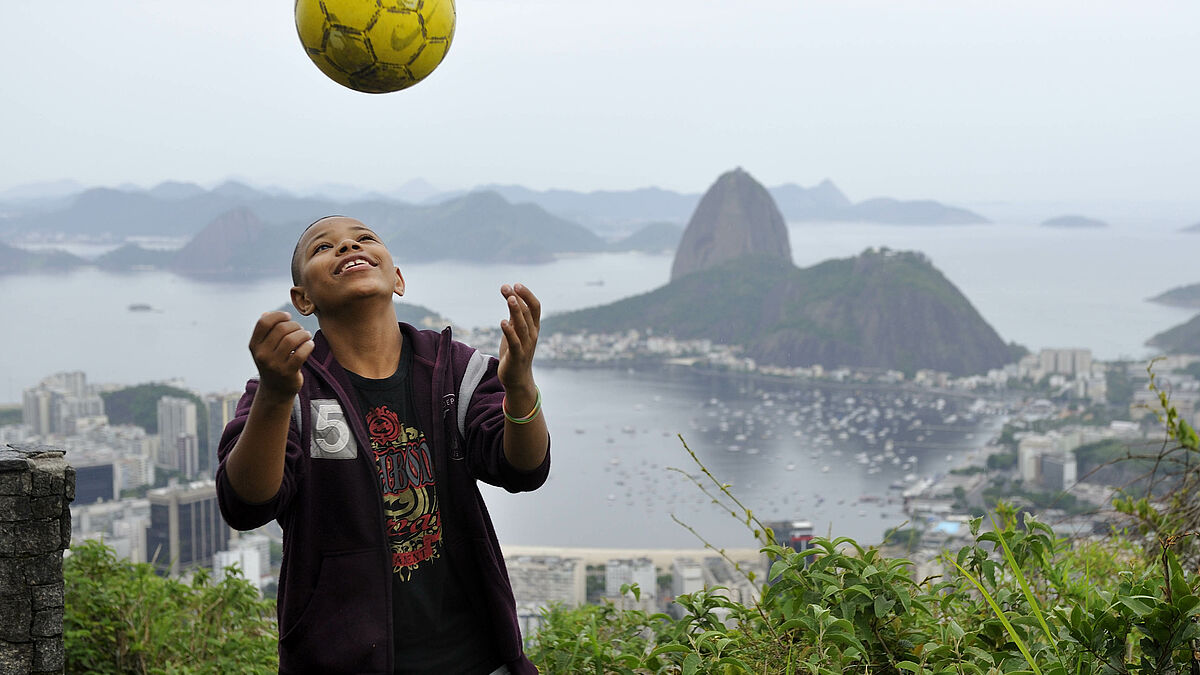 Gabriel Martins dos Santos (15 Jahre) mit einem Fussball vor der Kulisse des Zuckerhutes und der Bucht von Botafogo.