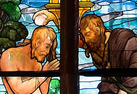 Ein Glasfenster zeigt Johannes den Täufer, der Wasser aus dem Jordan über das Haupt Christi gießt