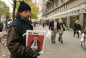 Ein Verkäufer der Hamburger Obdachlosenzeitung Hinz und Kunzt bietet auf dem Jungfernstieg in Hamburg Passanten die Zeitung zum Kauf an (Archiv).