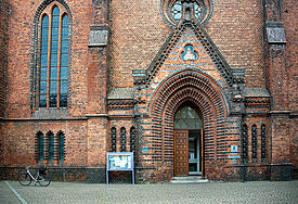 Eingang der St. Nikolaikirche in Kiel. Die Tür steht offen, ein Fahrrad ist vor der Kirche abgestellt.