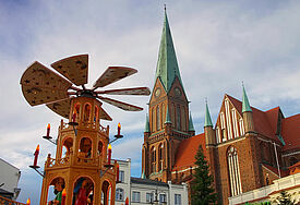 Der Schweriner Dom zur Adventszeit- im Vordergrund ist eine großer hölzerne Weihnachtspyramide vom  Schweriner Weihnachtsmarkt zu erkennen. 