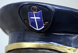 Schirmmütze mit Logo der Deutschen Seemannsmission (DSM), einem stilisierten Ankerkreuz.