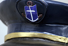 Schirmmütze mit Logo der Deutschen Seemannsmission (DSM), einem stilisierten Ankerkreuz.
