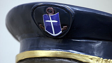 Schirmmütze mit Logo der Deutschen Seemannsmission (DSM), einem stilisierten Ankerkreuz.