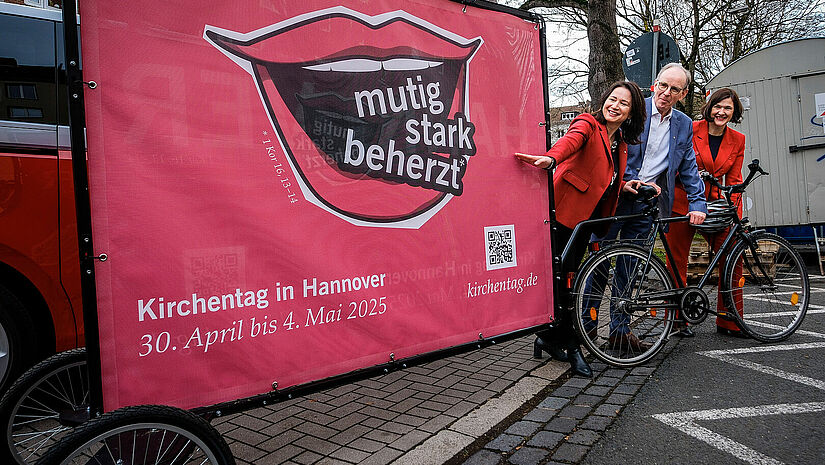 Anja Siegesmund (Kirchentagspräsidentin), Ralf Meister (Landesbischof Hannover) und Kristin Jahn (Kirchentagsgeneralsekretärin) stellen mit einem Plakat den Leitgedanken der Veranstaltung vor. 
