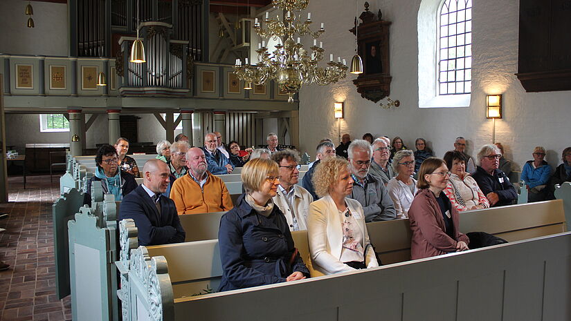 Menschen sitzen auf Kirchenbänken in einer kleinen Kirche