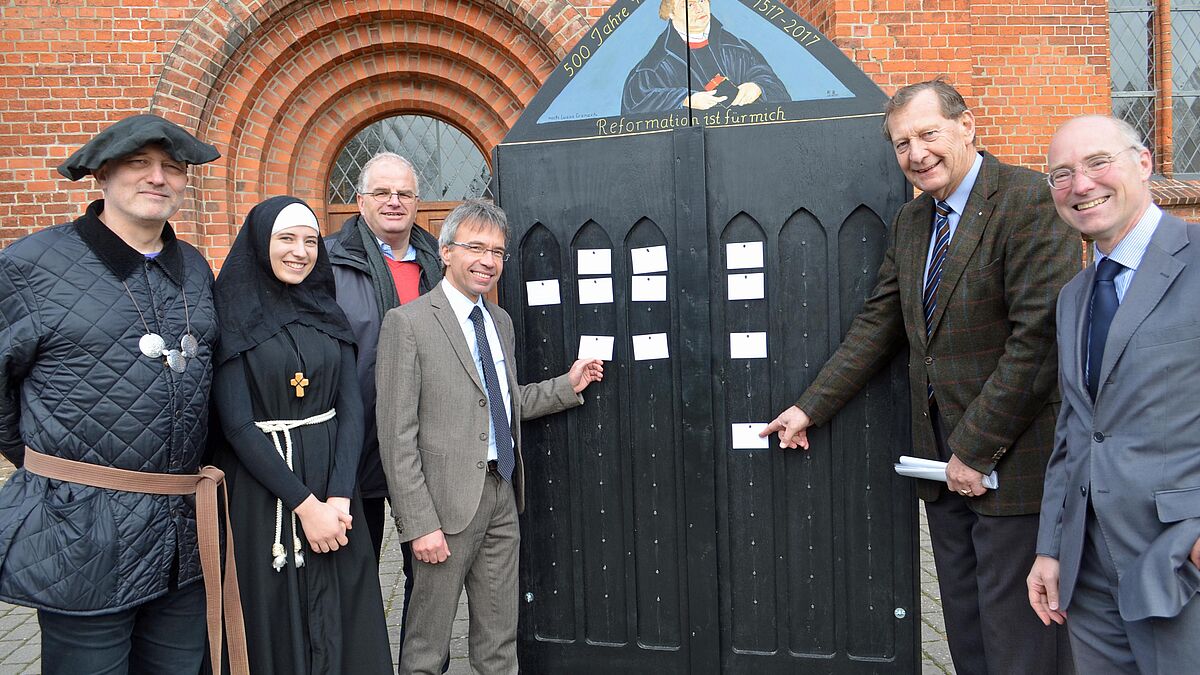 (von links) Pastor Carsten Baden-Rühlmann, Schülerin Laura Haustein, Pastor Roland Scheel, Propst Dr. Daniel Havemann und Präses Peter Wiegner mit Pastor Wolfgang Stahnke freuen sich auf eine spannende Wanderschaft der Thesentür.