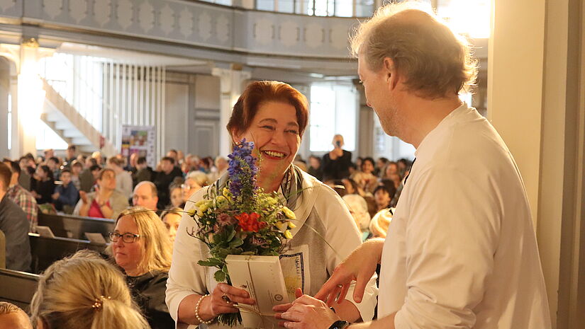 Stephan Reinke überreicht Musiklehrerin und Texterin Agnes John einen Blumenstrauß als Dank für ihre Mitarbeit.