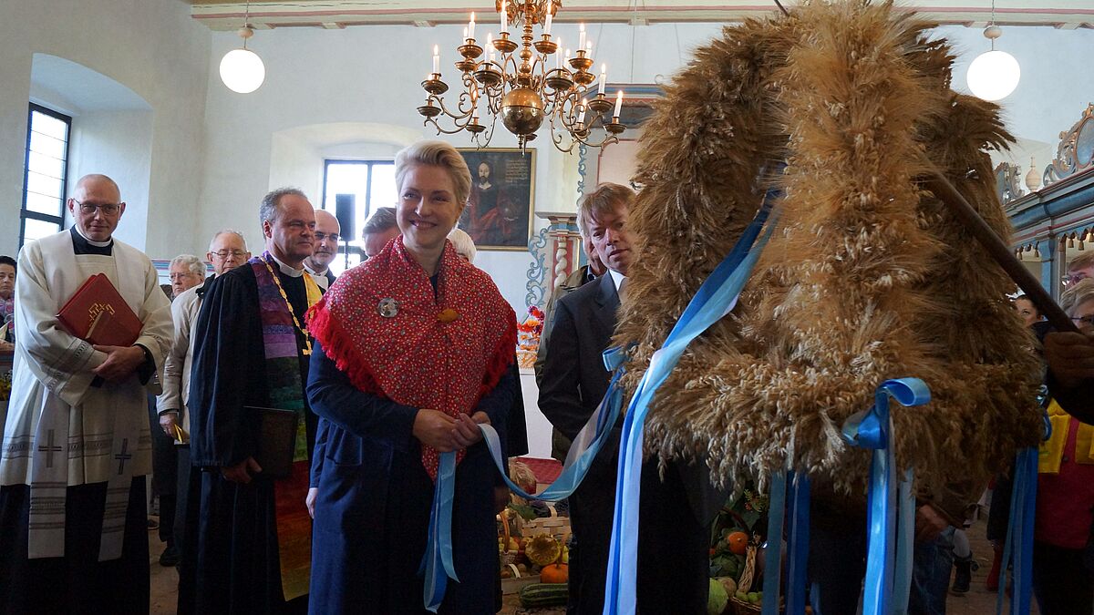 Die Erntekrone wird aus der Kirche hinaus zum Festumzug getragen. Mit dabei: Ministerpräsidentin Manuela Schwesig, Bischof Tilman Jeremias und der katholische Priester Marek Malesa (links).