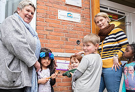Schon mal gucken, wo das Gütesiegel seinen Platz am Eingang findet: Kinder der Ev. Kita Noahs Arche zusammen mit Leiterin Birgit Griesbach (links) und der Qualitätsbeauftragten Meike Roetz (rechts).
