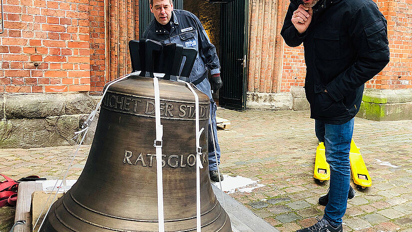 Glocke auf Holzpodest vor der Kirche