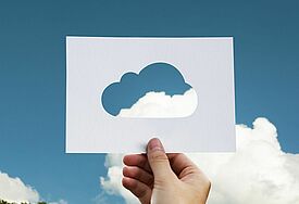 Eine Hand hält eine Wolkenschablone gegen den blauen Himmel