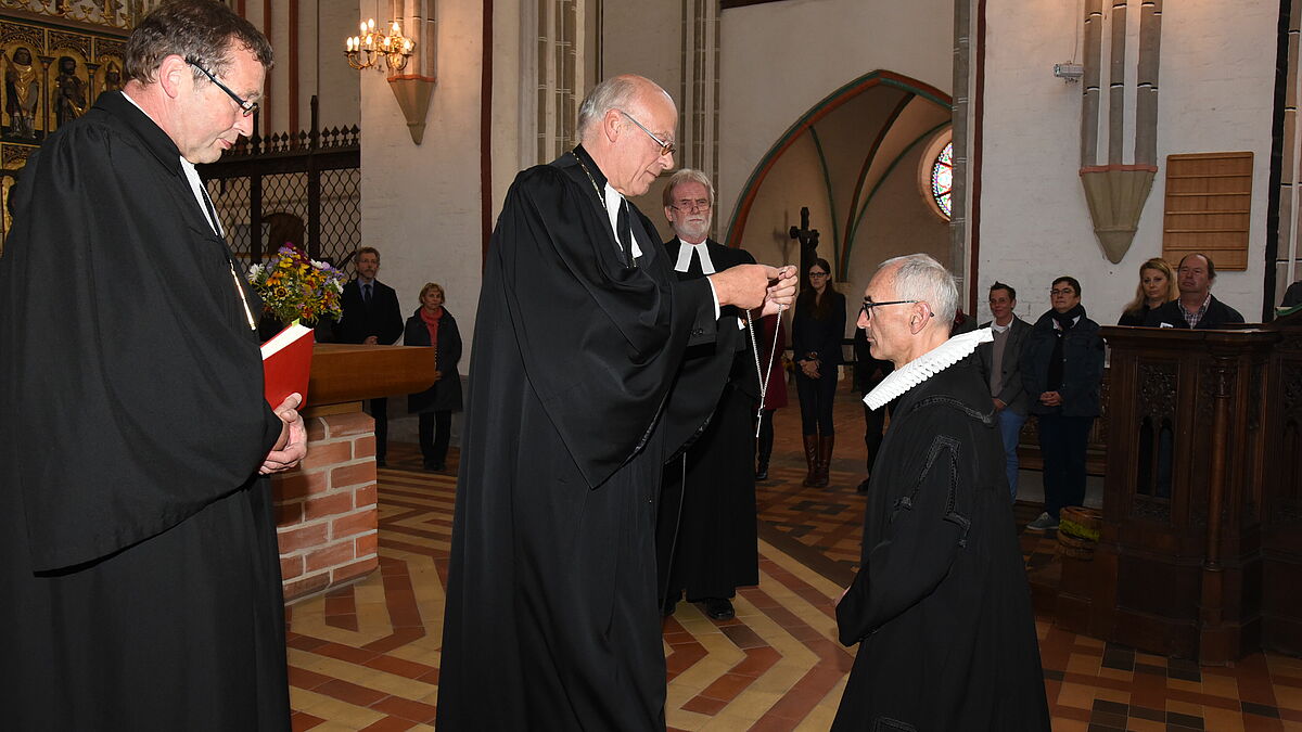 Landesbischof Gerhard Ulrich (Mitte) überreichte Diakoniepastor Paul Philipps (r.) das Amtskreuz im Schweriner Dom.