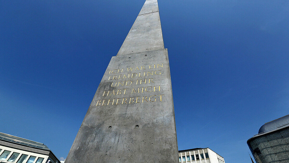 Der Obelisk des Künstlers Olu Oguibe (52) zeigt auf den vier Seiten das Jesus-Zitat aus dem Matthäus-Evangelium "Ich war ein Fremdling und ihr habt mich beherbergt" in Deutsch, Türkisch, Englisch und Arabisch.