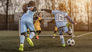 Mädchen spielen Fußball und rennen auf ein Tor zu.