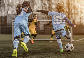 Mädchen spielen Fußball und rennen auf ein Tor zu.