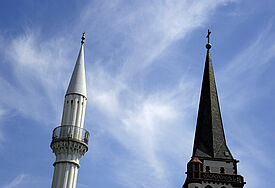 Kirchturm und Minarett stehen in Mannheim nebeneinander (Symbolbild).