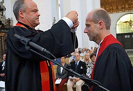 Bischof Jeremias überreicht das Amtskreuz an Propst Tobias Sarx. 
