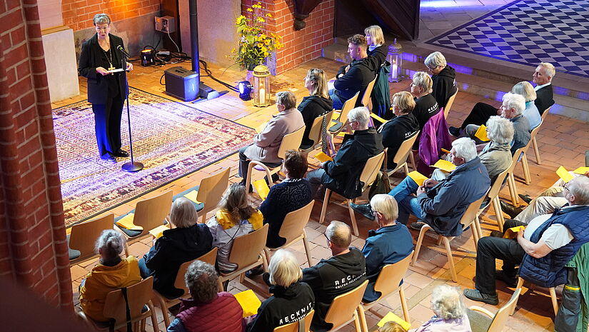 Blick von oben in einer Kirche. die Stuhlreihen sind besetzt. Vorne predigt die Landesbischöfin.
