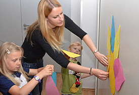 Erzieherin Dörte Meckes hängt mit Norwin (4) und Emma (6) die von den Kindern gestaltete Trauerblume auf.