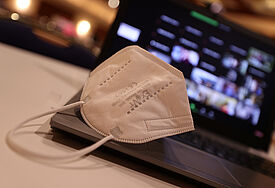 Eine FFP2-Maske liegt auf einem aufgeklappten Laptop.