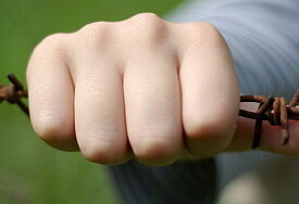 Hand am Stacheldrahtzaun