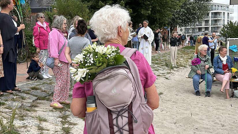 Eine Frau trägt in ihrem Rucksack einen Strauß weiter Blumen.