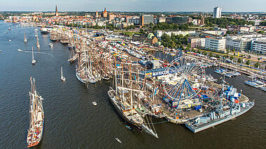 Blick von oben auf die Stadt mit Gebäuden, Schiffen und Riesenrad