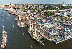 Blick von oben auf die Stadt mit Gebäuden, Schiffen und Riesenrad