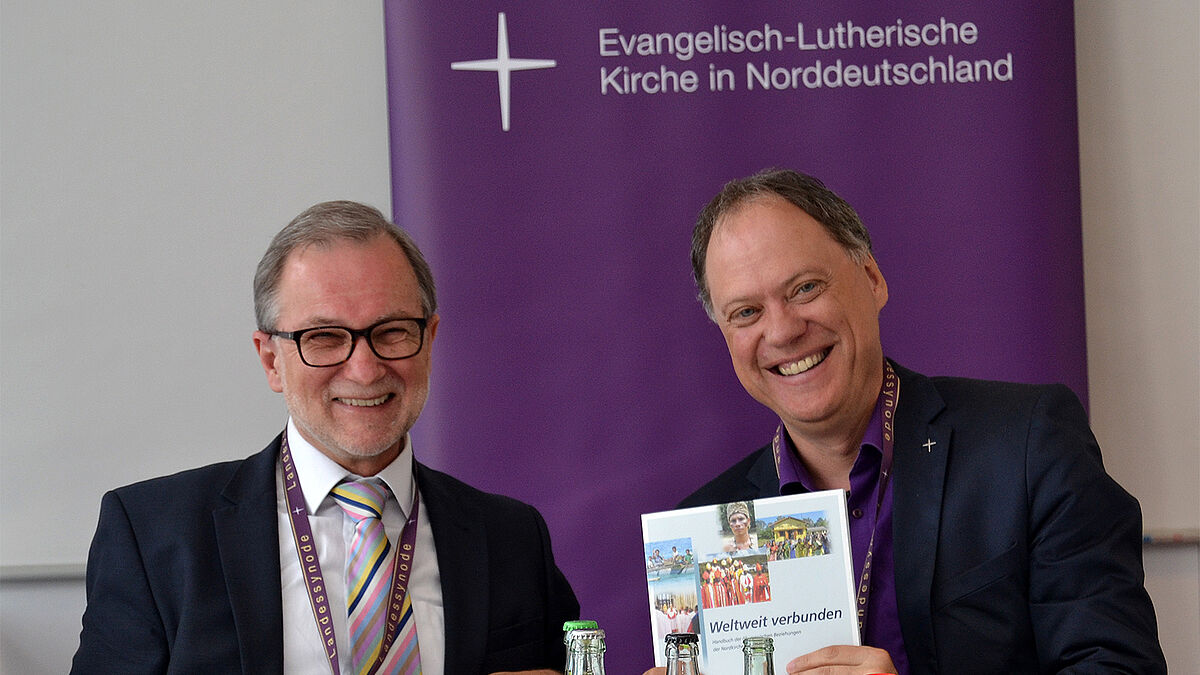 Präses Dr. Andreas Tietze (re) erhielt die neue Broschüre des Zentrums für Ökumene und Mission - nordkirche weltweit von Direktor Dr. Klaus Schäfer (li)auf der Synoden-Pressekonferenz