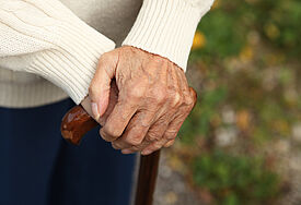 Eine Seniorin stützt sich auf ihren Gehstock